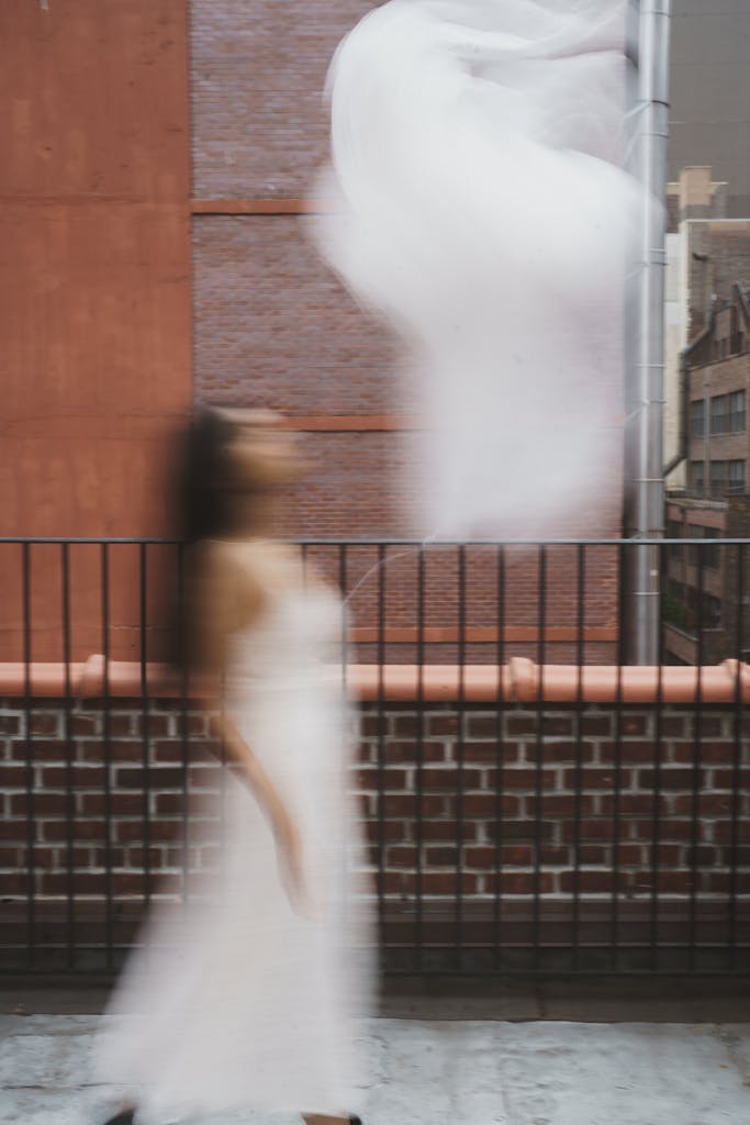 A blurred image of a woman walking past a brick wall in New York City