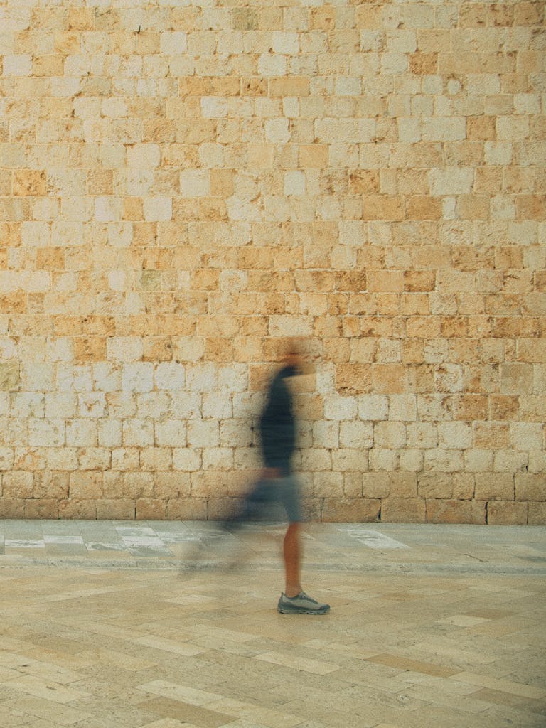 A person in motion captured with long exposure against a historic stone wall in Dubrovnik, Croatia.